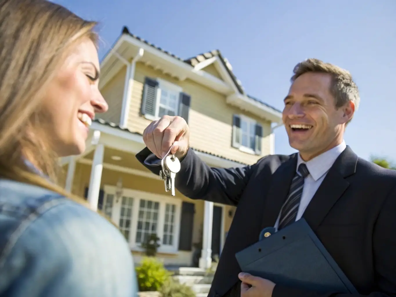 A photograph of a real estate agent handing over keys to a new homeowner in Dubai, symbolizing the successful completion of a secondary market property transaction.